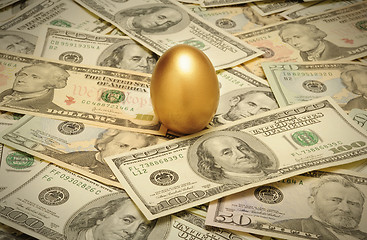 Image showing Gold nest egg on a layer of cash of various American banknote de