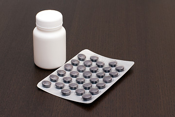Image showing White vial, black pills