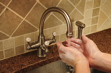 Image showing Soapy hand washing under flowing water out of a faucet