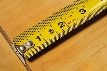 Image showing Yellow tape measure measuring a piece of wood