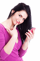 Image showing beautiful young woman on the phone, smiling at the camera with one finger to touch the mouth