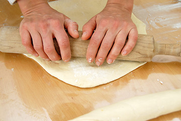 Image showing Hands on rolling pin over dough