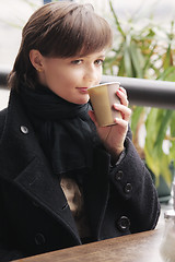 Image showing Woman in black coat with cup