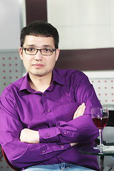 Image showing Guy in cafe with glass of wine arms folded