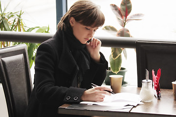 Image showing Woman in black coat working in cafe