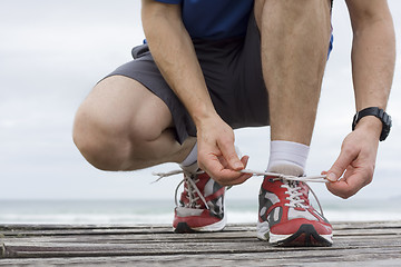 Image showing Runner tying shoelace