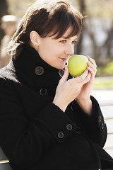 Image showing Woman in black smelling apple