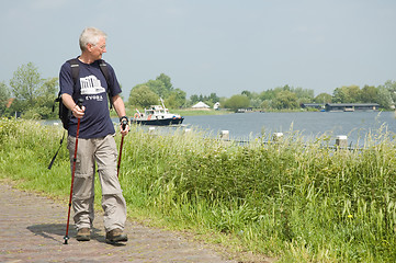 Image showing Senior man doing a Nordic Walk on a sunny day.