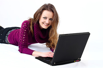 Image showing lying and smiling attractive woman with a laptop