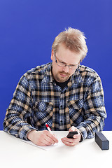 Image showing Man writes notes at his office desk