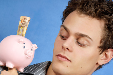 Image showing Young man with piggy bank