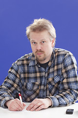 Image showing Man writes notes at his office desk