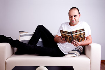 Image showing man lying on the sofa reading a book