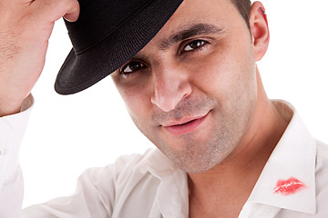 Image showing seductive man greeting with his hat, the shirt with lipstick mark
