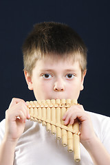 Image showing Boy in white playing panflute