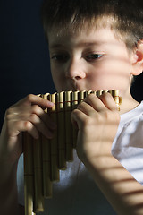 Image showing Boy playing panflute in darkness