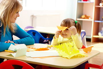 Image showing Teacher and little girl play with color paper