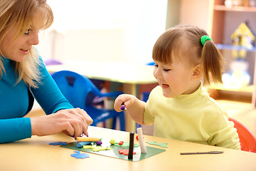 Image showing Teacher and little girl play with plasticine