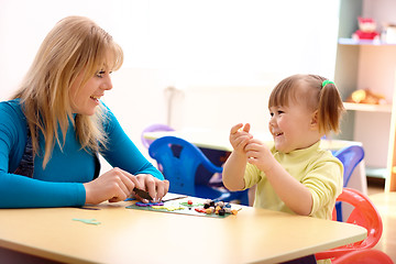 Image showing Teacher and little girl play with plasticine