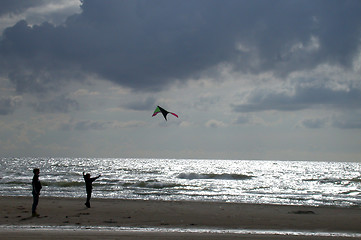 Image showing To børn leger på stranden med drage