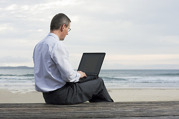 Image showing Businessman working with laptop on a beach