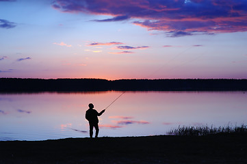 Image showing The fisherman with a fishing tackle at lake on a sunset