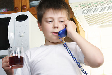 Image showing Boy in white with tea talking phone