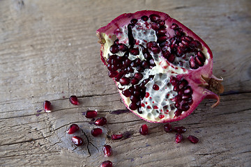 Image showing Pomegranate with arils on wooden board