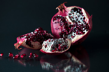 Image showing Sliced Pomegranate with arils on black glass