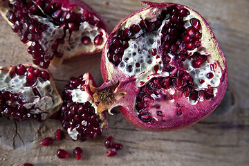 Image showing Pomegranate with arils on wooden board