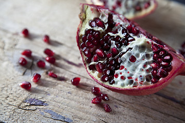 Image showing Pomegranate with arils on wooden board
