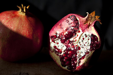 Image showing Pomegranate with arils on wooden board