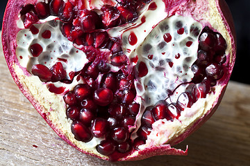 Image showing Pomegranate with arils on wooden board