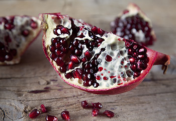 Image showing Pomegranate with arils on wooden board