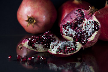 Image showing Sliced Pomegranate with arils on black glass