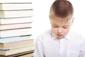 Image showing Boy sitting at stack of books