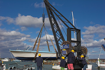 Image showing Family lowering boat into water