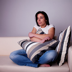 Image showing beautiful young woman,  on the couch watching TV, scared