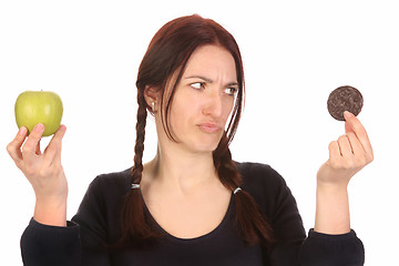 Image showing woman choosing between chocolate cookies and apple