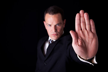 Image showing Businessman with his hand raised in signal to stop, isolated on black background, Studio shot