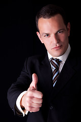 Image showing businessman giving consent, with thumb up, isolated on black background. Studio shot.