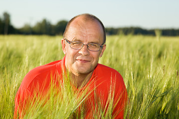 Image showing Middle-aged man smiling behind hay