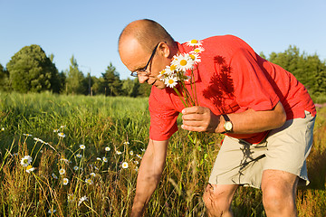 Image showing Middle-aged man picking up flowers