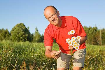 Image showing Middle-aged man picking up flowers