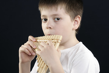 Image showing Boy in white shirt playing bamboo panflute
