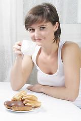Image showing Smiling woman drinking tea with cakes