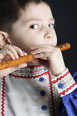Image showing Little boy playing wooden flute