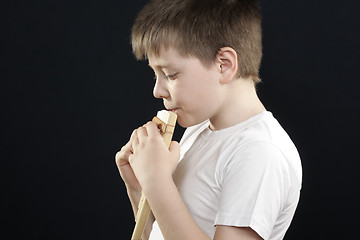 Image showing Kid in white playing panflute sideview