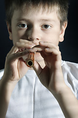 Image showing Boy in white playing wooden pipe