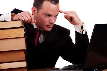 Image showing businessman on desk with books, looking at the computer